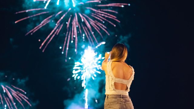 Young woman admiring and photographing firework display