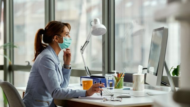 young white woman working at desk with coronavirus mask on