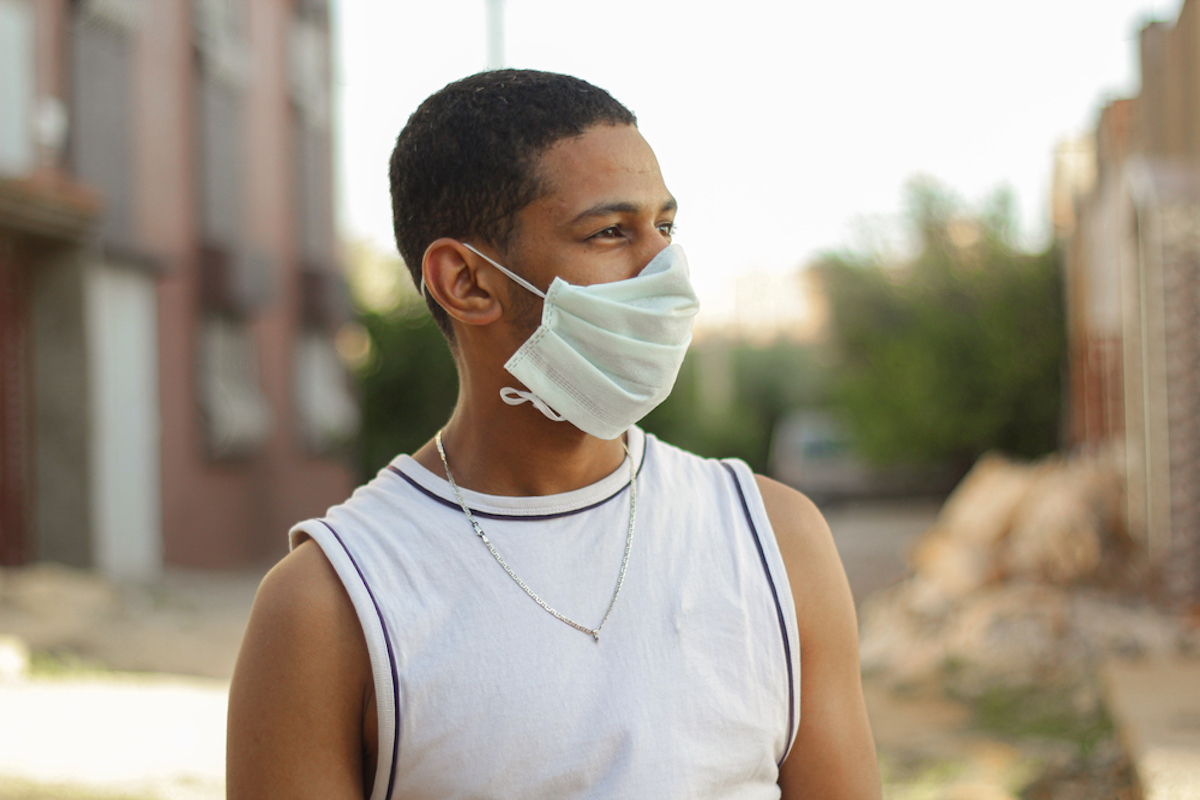Portrait of African American man out and about in the city streets during the day, wearing a face mask against the coronavirus.
