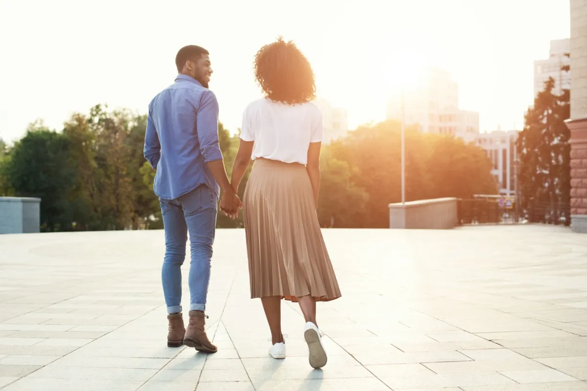 young black couple holding hands outdoors at sunset