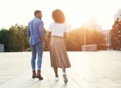 young black couple holding hands outdoors at sunset