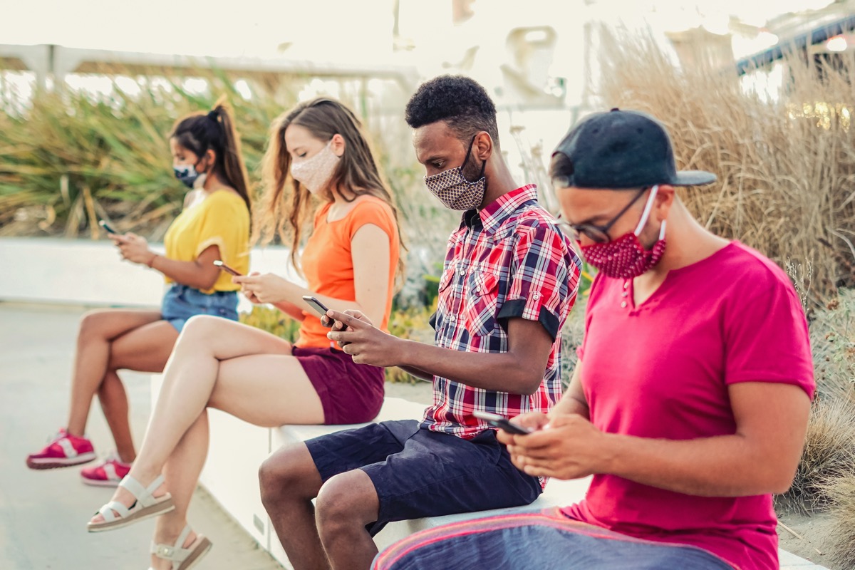 Young people using phones and wearing masks