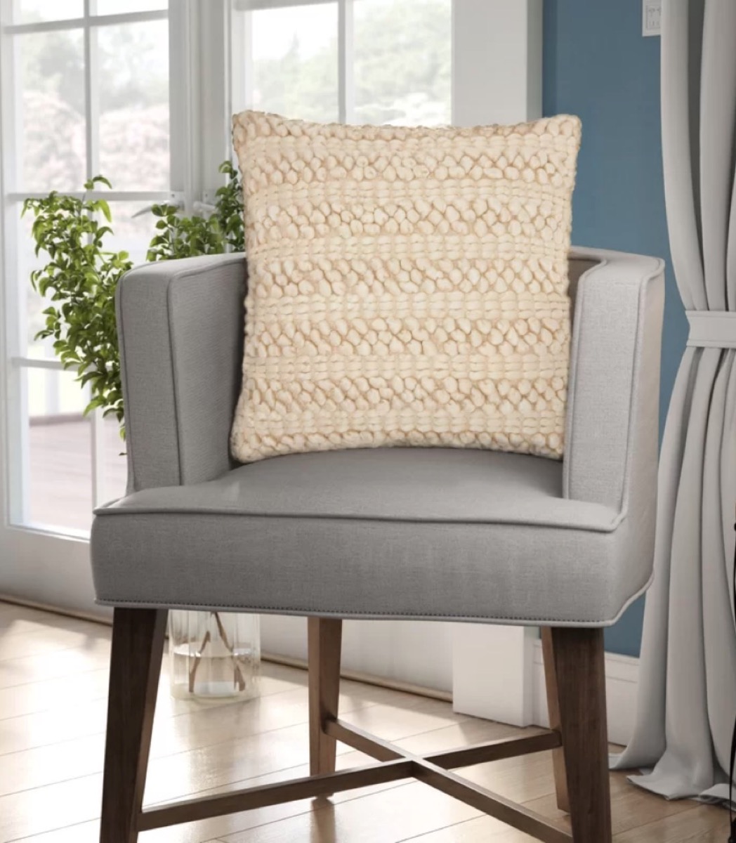 gray chair with striped tan pillow on it