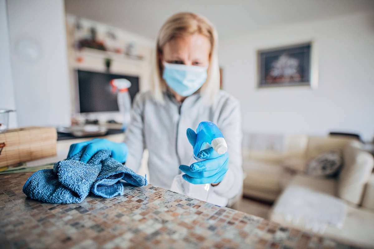 One mature woman cleaning and doing disinfection on all surfaces in her house.