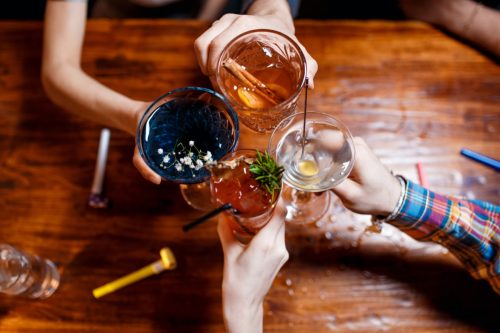 приятели, цъкащи по чаши с различни алкохолни коктейли на масата, изглед отгоре