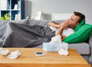 Man with a cold on the couch blowing his nose