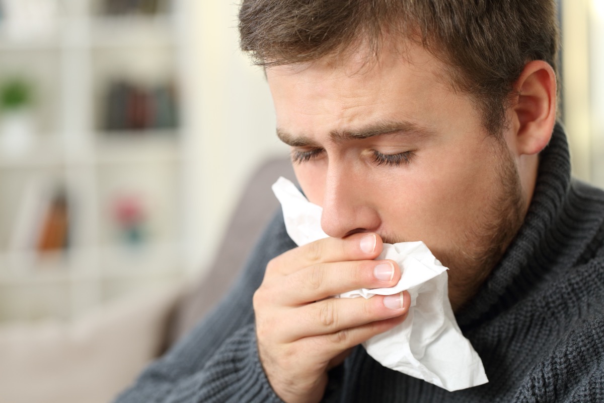 Man with phlegm coughing into tissue at home