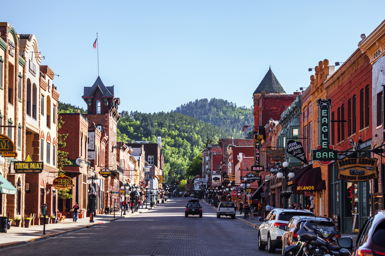 The main street of Deadwood, South Dakota with cars and shops in view.
