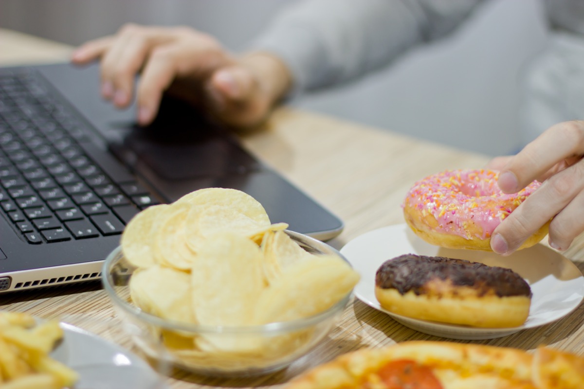 Woman eating donuts and chips while working form home