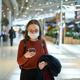 Teenager wearing medical mask protecting herself against virus in a food court of a shopping mall or airport lobby