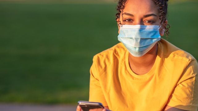 Girl wearing face mask outside while on phone