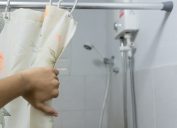 hand pulling back shower curtain