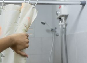 hand pulling back shower curtain