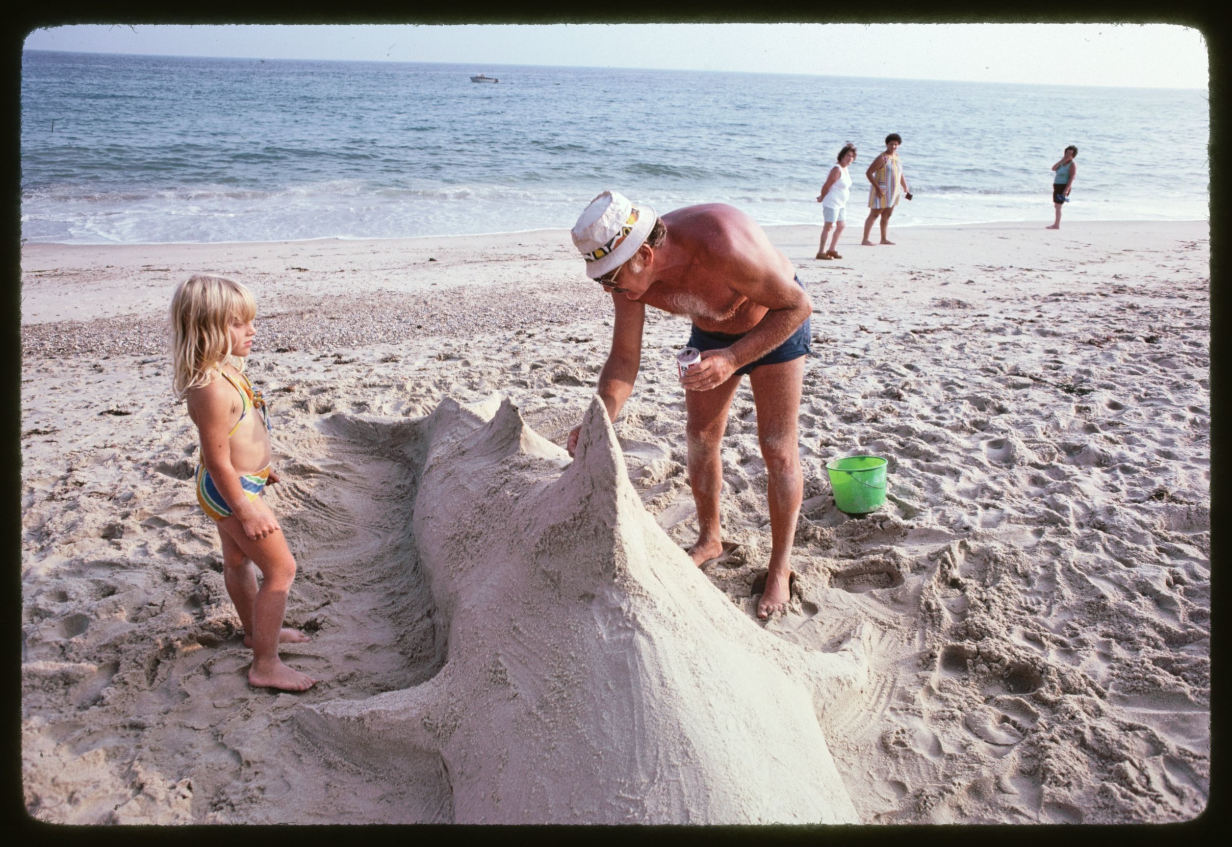a man and a child build a sand sculpture