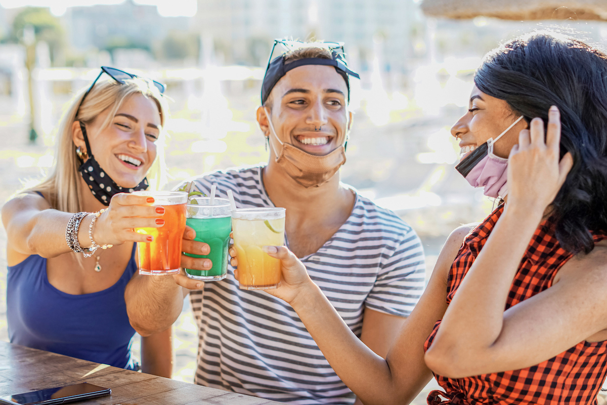 young people drinking with masks on chin