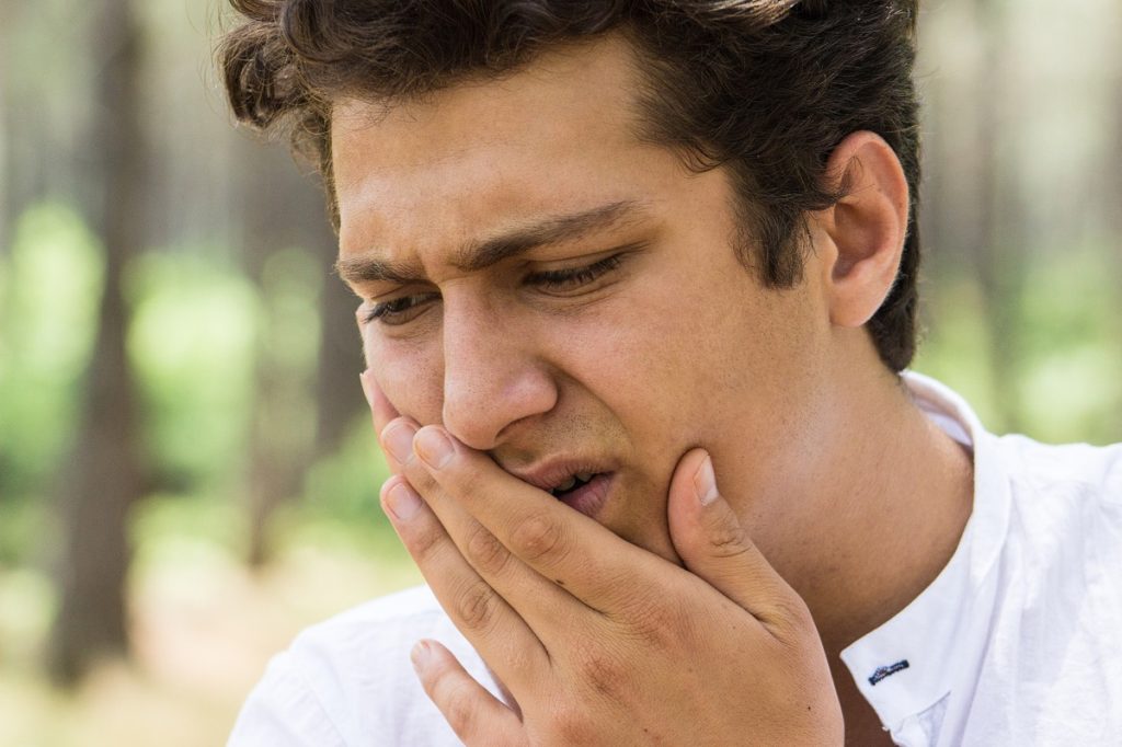 Man holding mouth in discomfort