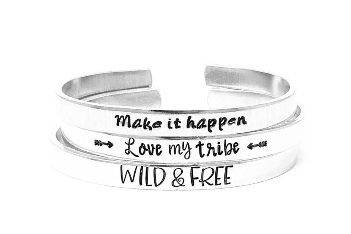 personalized silver bracelets, stack of three, first says "make it happen," second says "love my tribe," third says "wild & free"