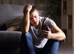 sad man looking at phone and holding his hand