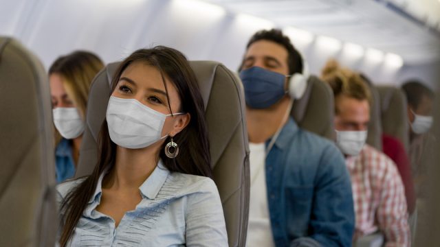 Travelers on a plane wearing face masks during the COVID-19 pandemic