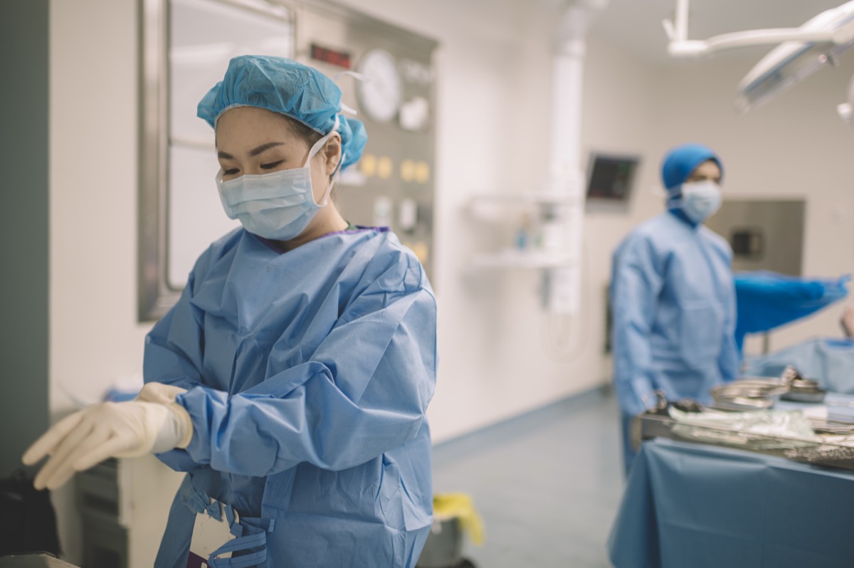 a female surgeon doctor is wearing surgical gloves before the surgery in operating room