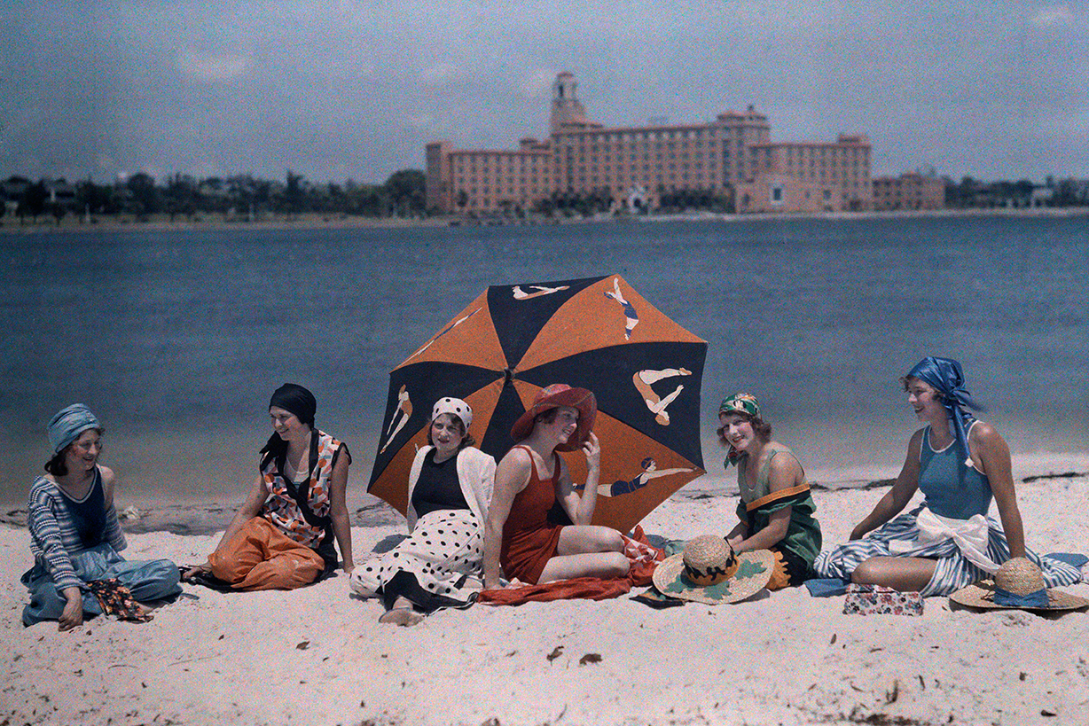 a group of women sit at the beach in the 1930s