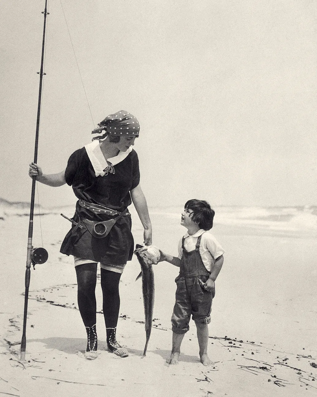a woman and a young child catch a fish on the beach