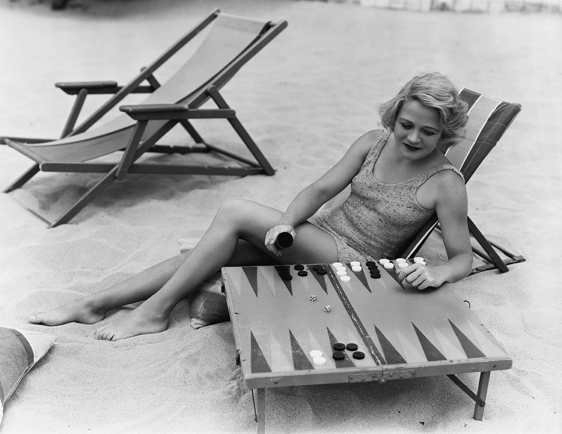 a woman plays backgammon on the beach
