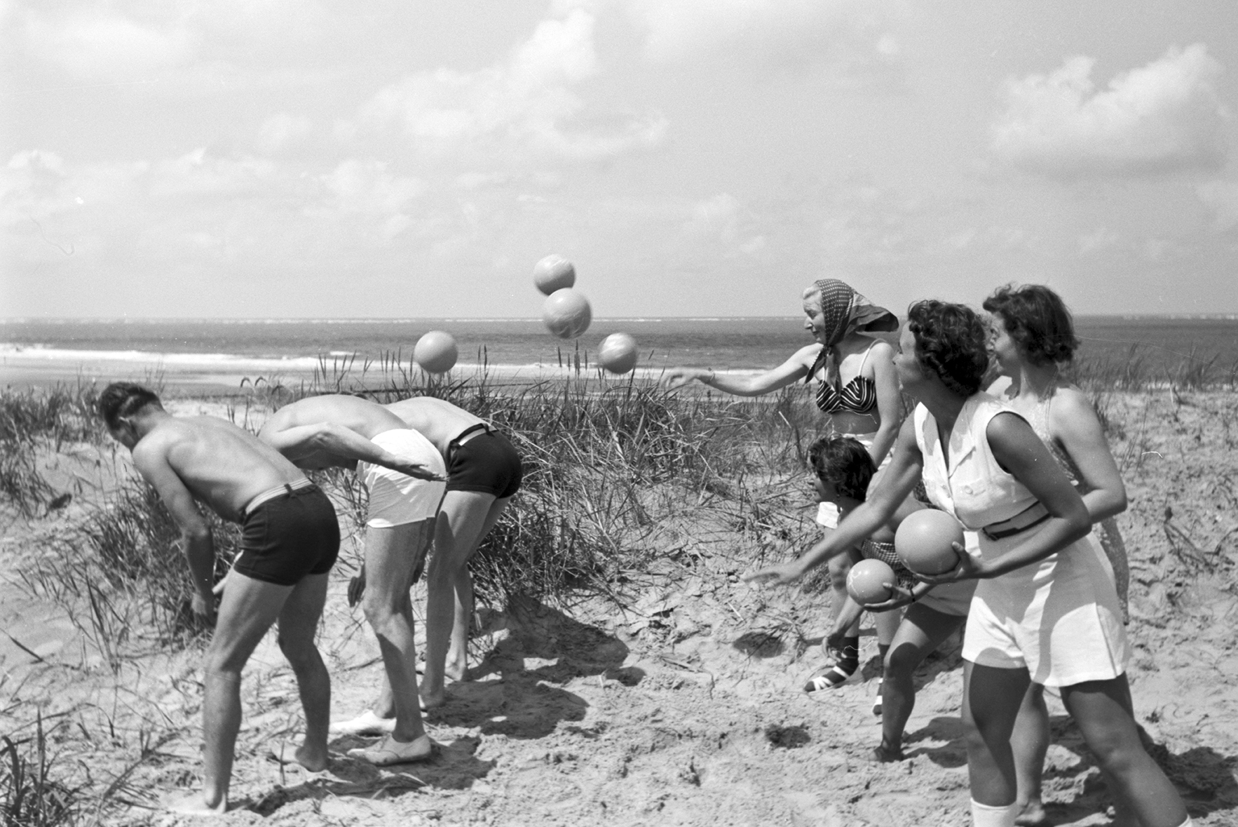 a group of friends play catch at the beach