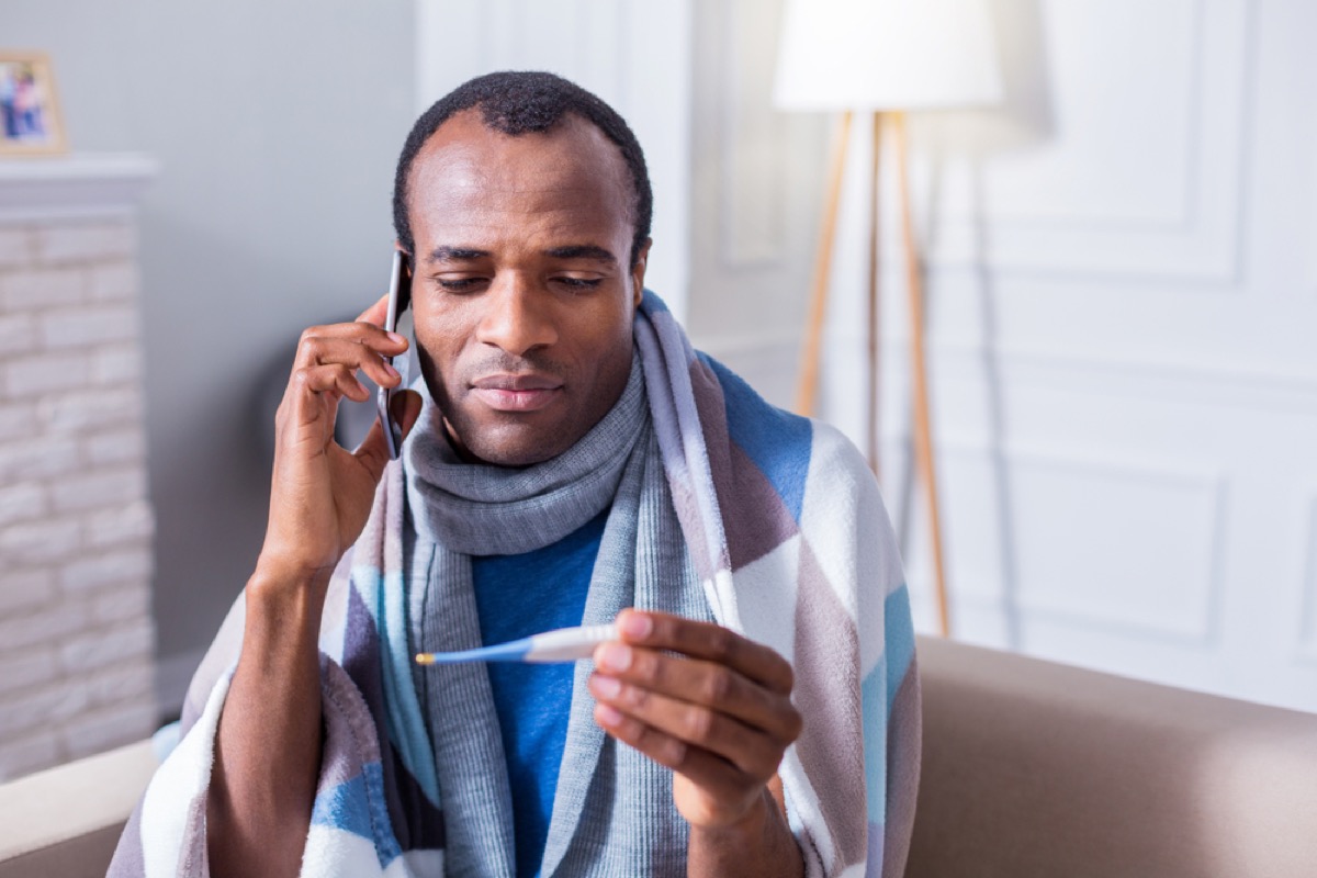 black man checking his temperature and making a phone call
