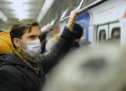 white man with face mask on crowded subway train