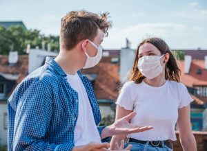 white man and white woman with face masks talking outside