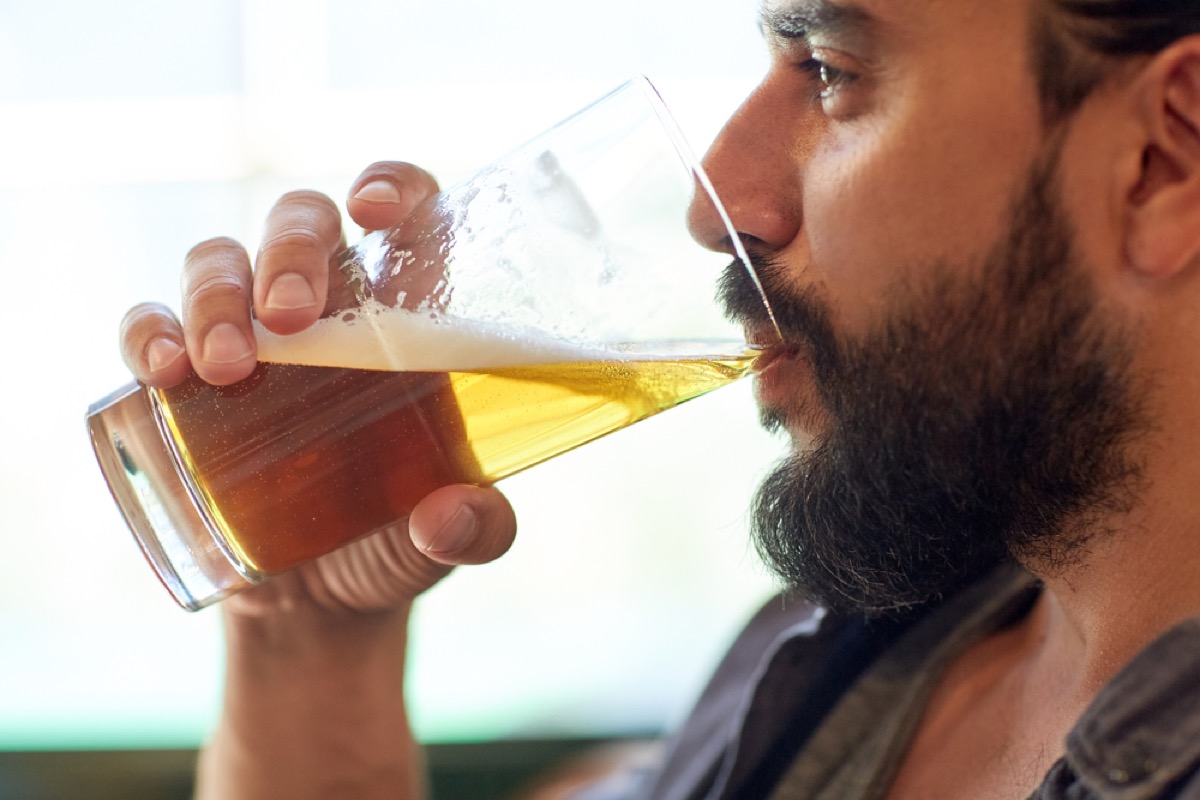 close up of bearded man drinking a glass of beer