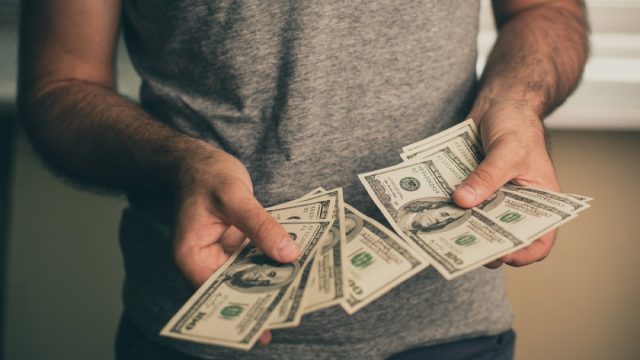 close up of man's hands holding hundred dollar bills