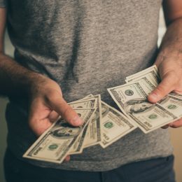 close up of man's hands holding hundred dollar bills