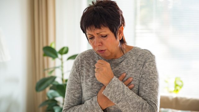 older white woman coughing at home