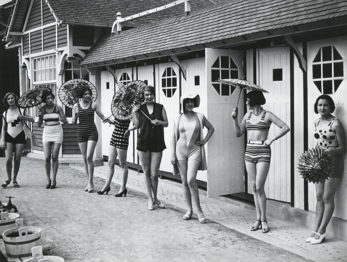French women pose in the latest fashionable bathing suits outside their beach cabanas at Dieppe. Ca. 1925.