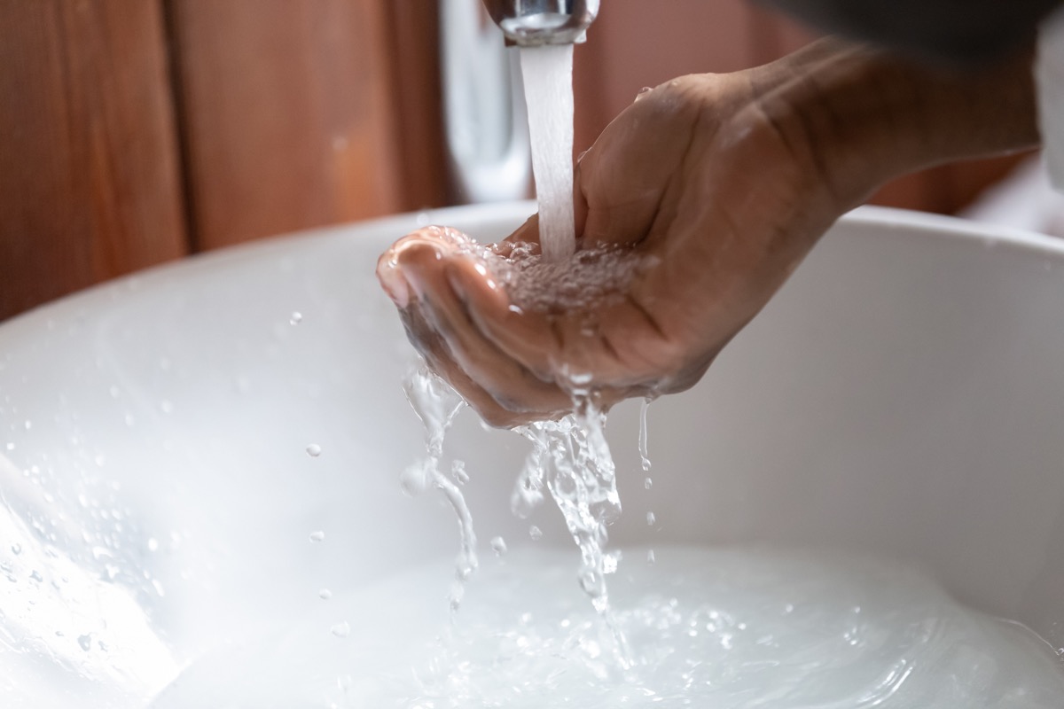 Close up view man hand gathering clear water pouring from faucet into the human palm
