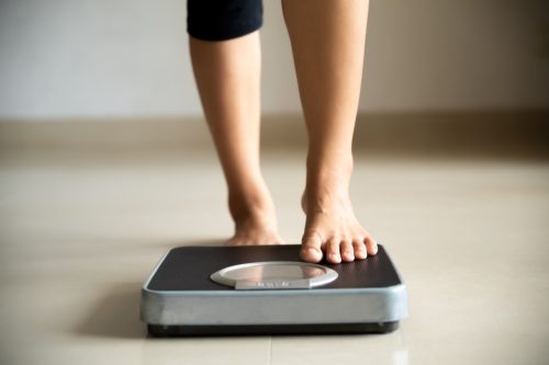 Woman stepping on scale to check weight