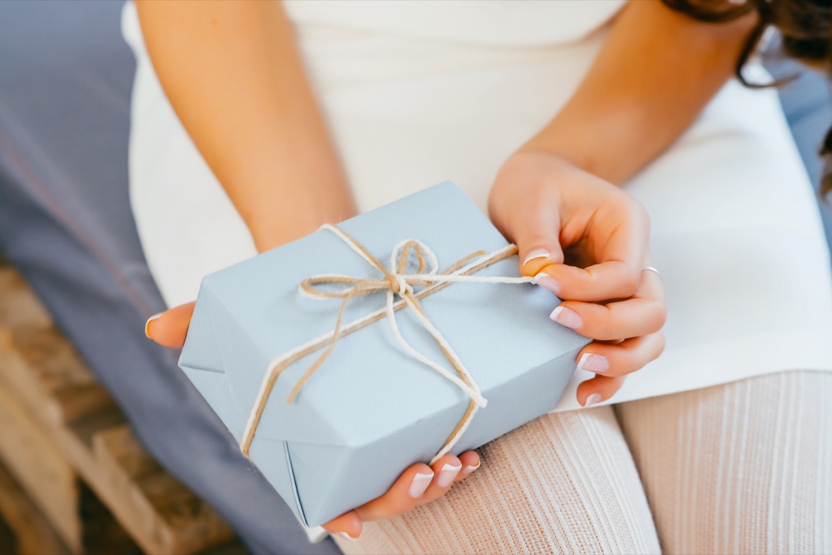 white hands opening ribbon on gift wrapped present