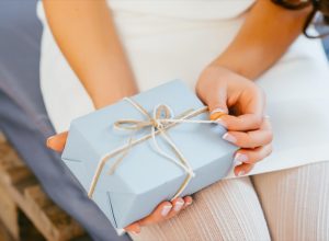 white hands opening ribbon on gift wrapped present