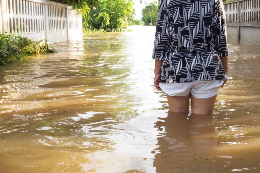 Žena se brodí záplavy v jejím domě.  Detailní záběr na její noze.  Záplavy v provincii Loei, Thajsko.