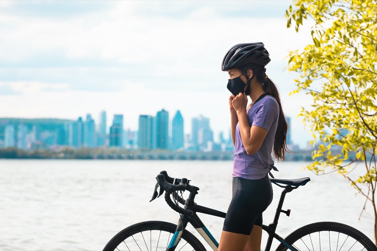 young woman biking in coronavirus mask