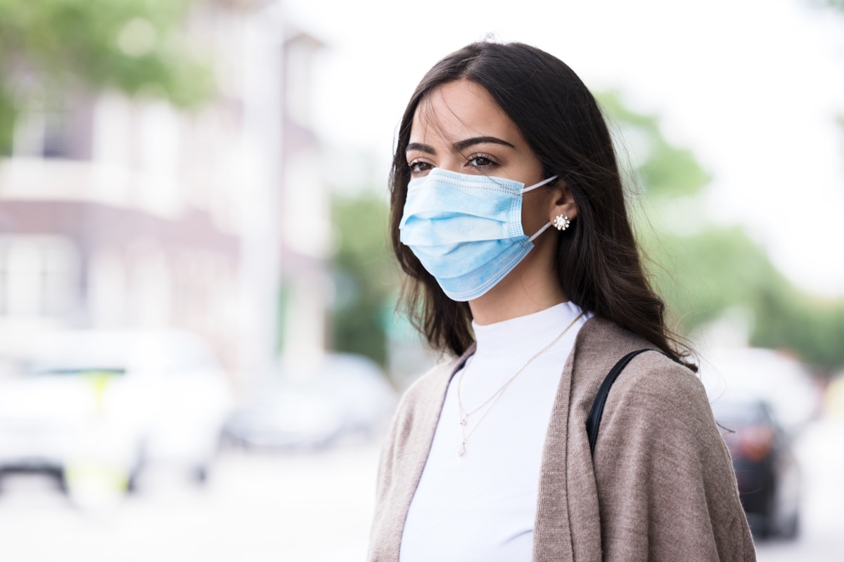 Walking home after class, the young woman wears her protective mask because of the coronavirus epidemic.