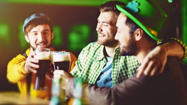 Three young white male friends celebrating St. Patrick's Day in an Irish pub