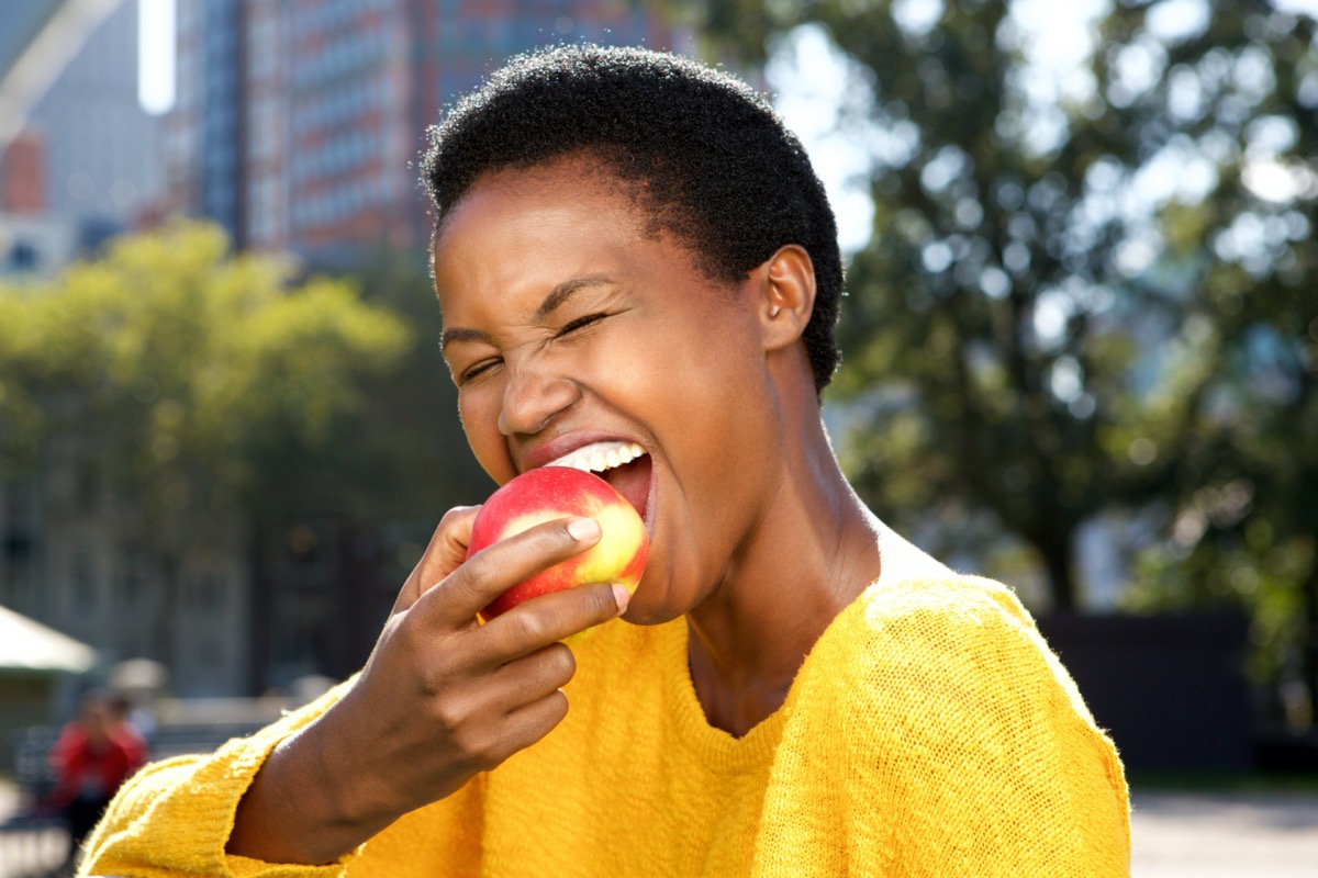 Young black woman eating an apple