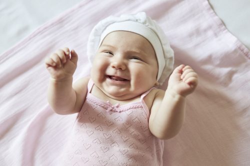 Nettes Babymädchen kitzelte auf rosa Decke