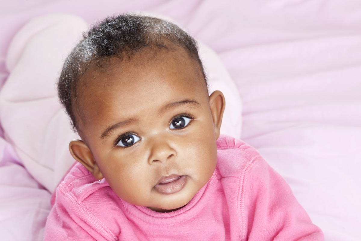 Portrait of 6 months old female baby lying on bed.