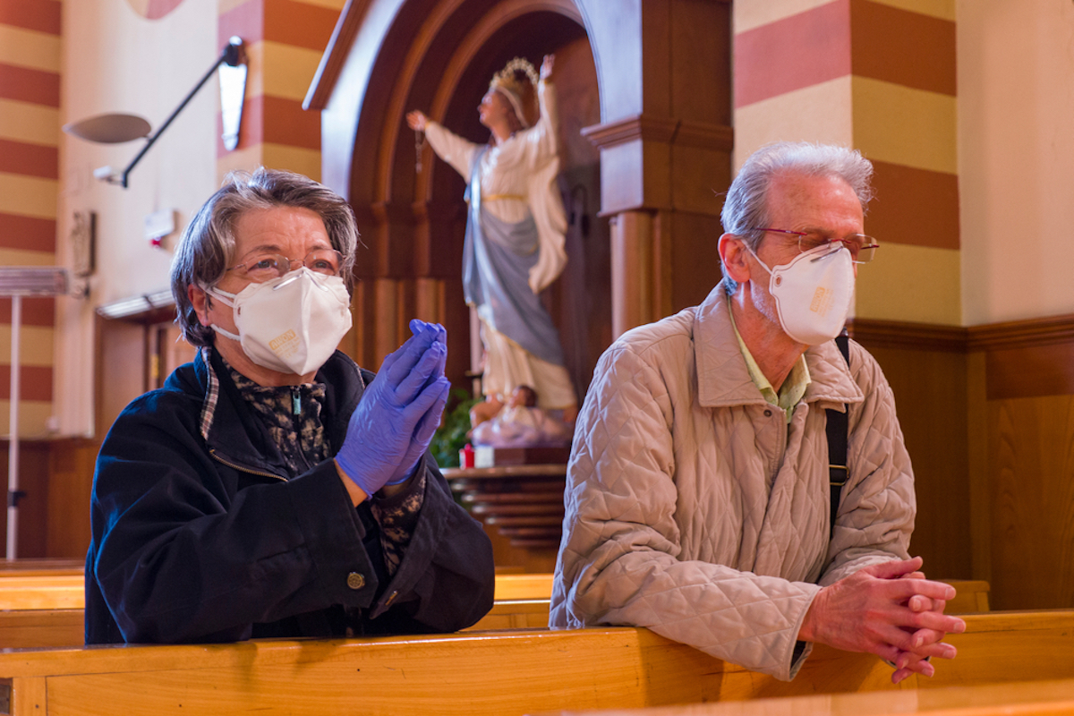 senior couple kneeling at church while wearing masks