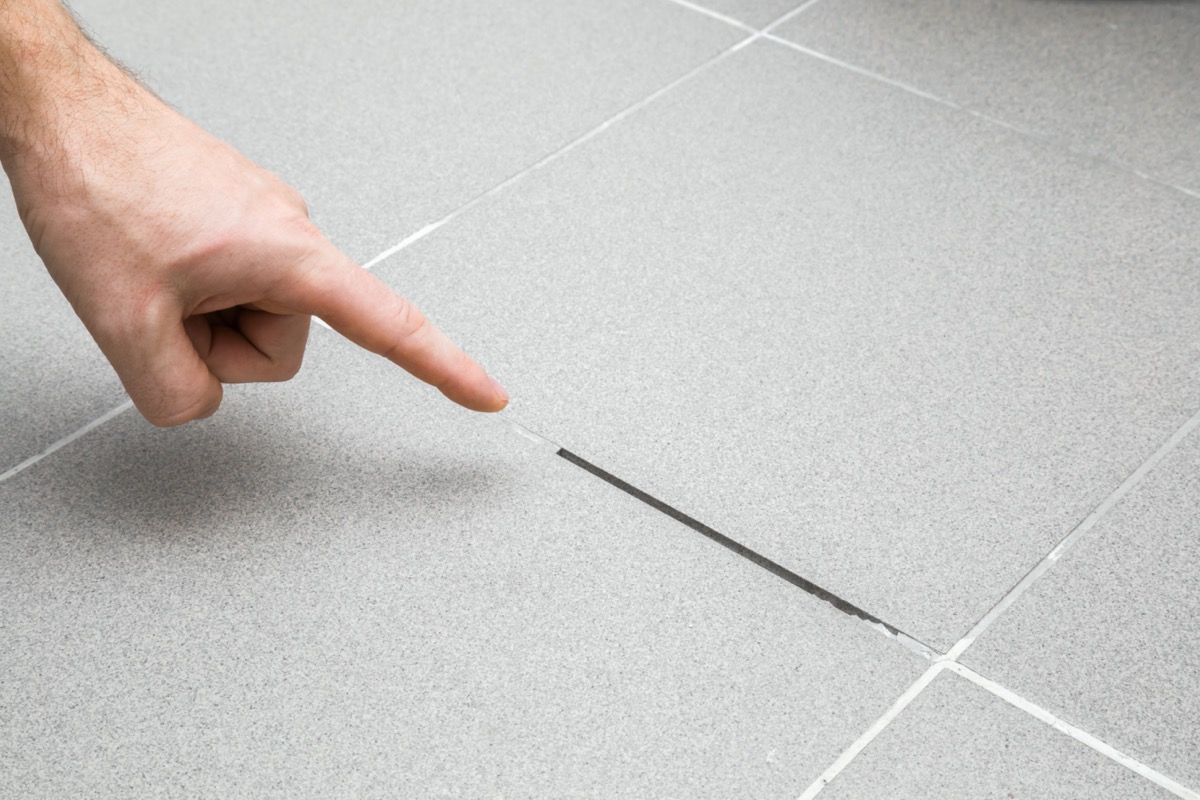 white hand pointing to bathroom grout