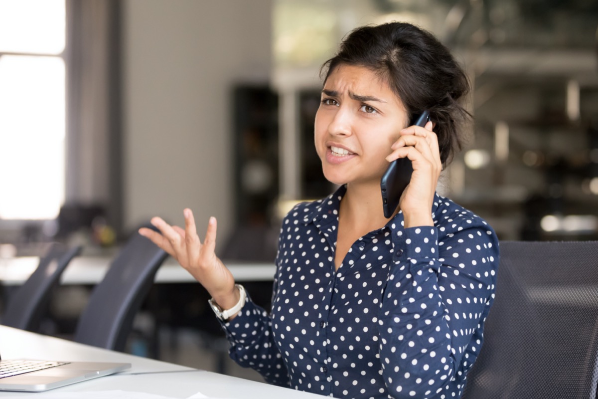 young indian woman looking angry on a phone call at work